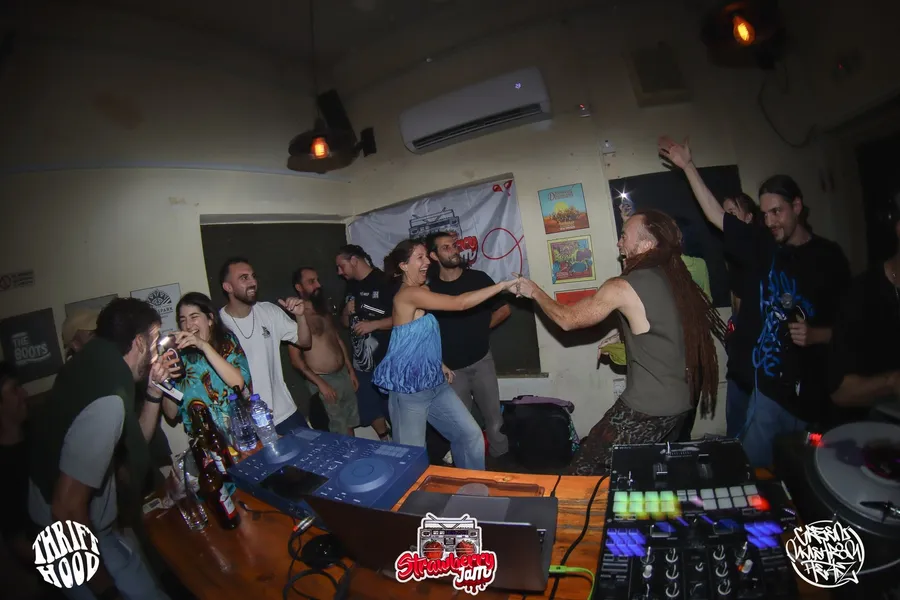 A group of part-goers dancing together by the DJ booth gallery image 2